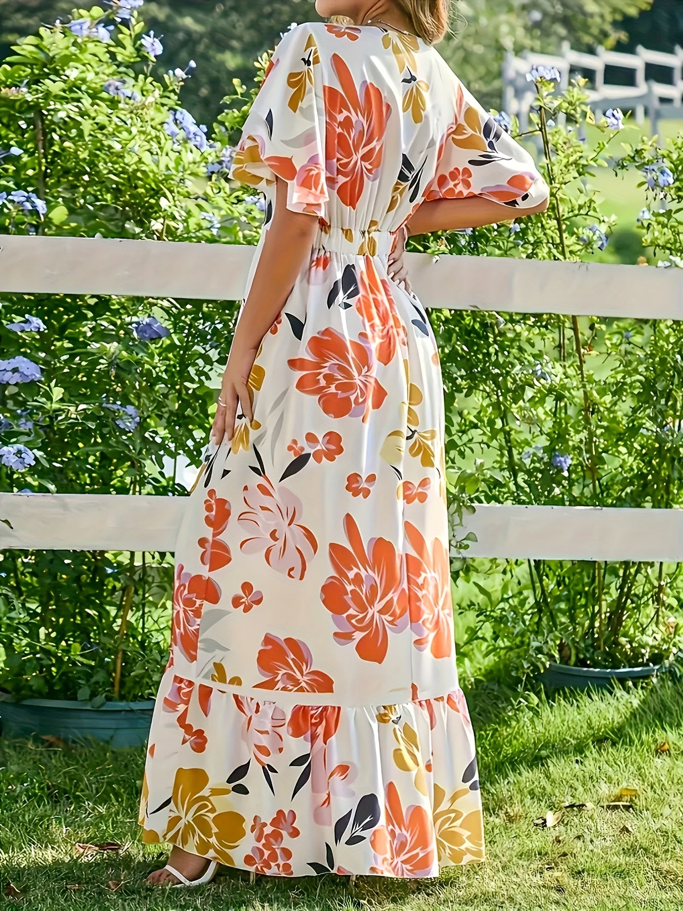 Lange jurk met grote bloemen in warme oranje en gouden tinten
